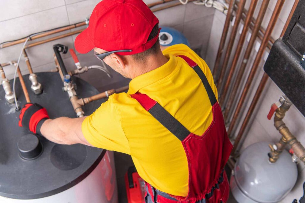 técnico  de espaldas reparando caldera en sala de calderas 